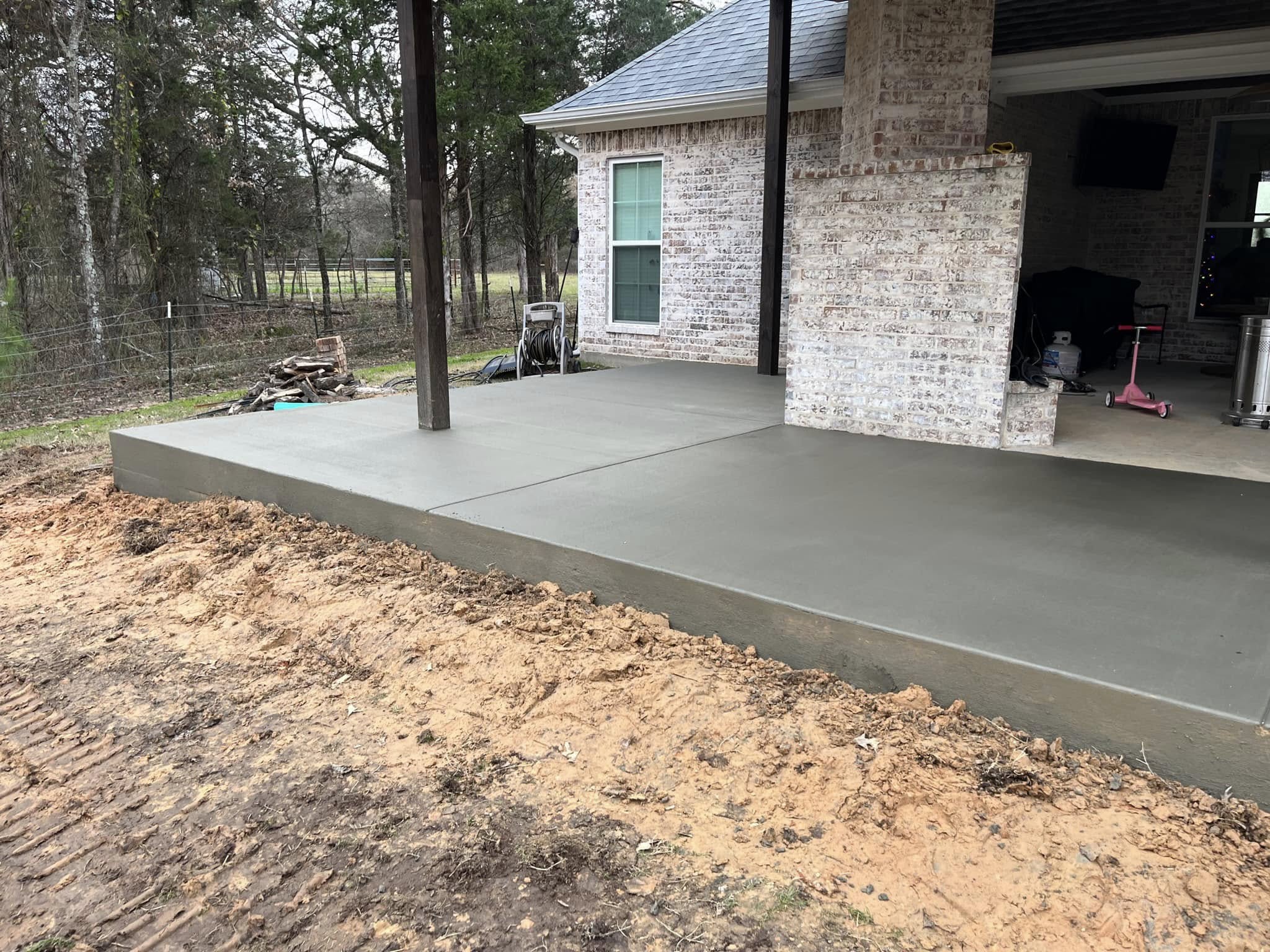 Freshly poured concrete patio extension at residential home, providing durable outdoor living space – Hood Lawn Care and Services