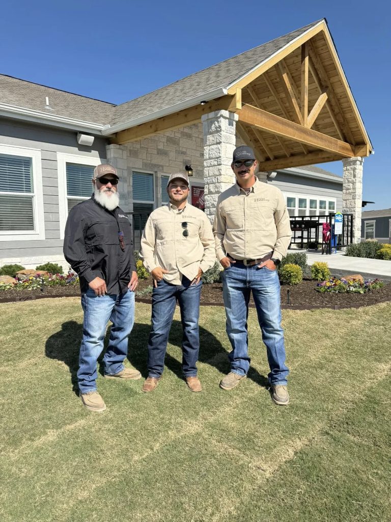 Hood Lawn Care team standing outside a landscaped property in Texas