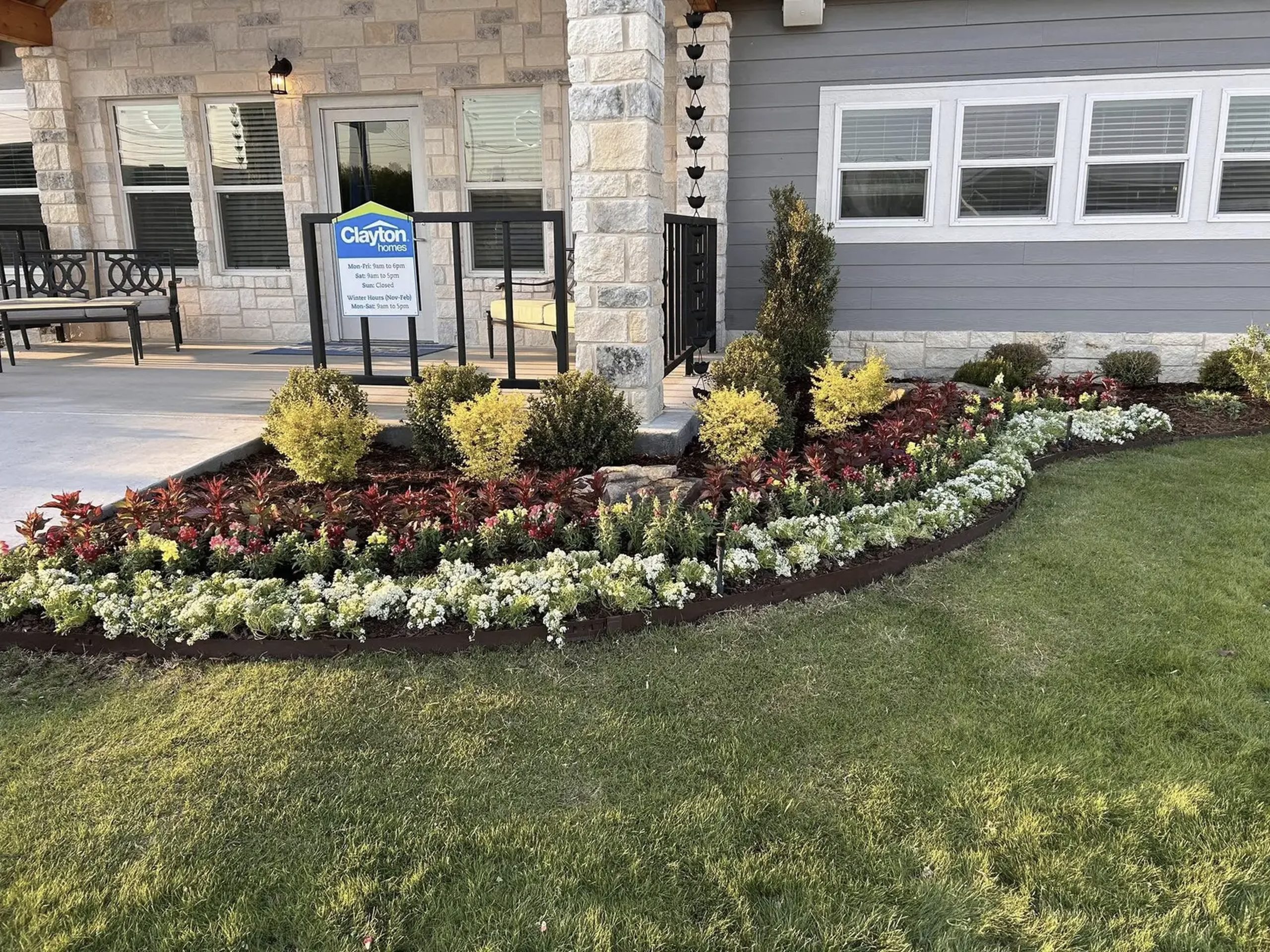 Commercial landscape with colorful flower bed and manicured shrubs in front of Clayton Homes office by Hood Lawn Care.