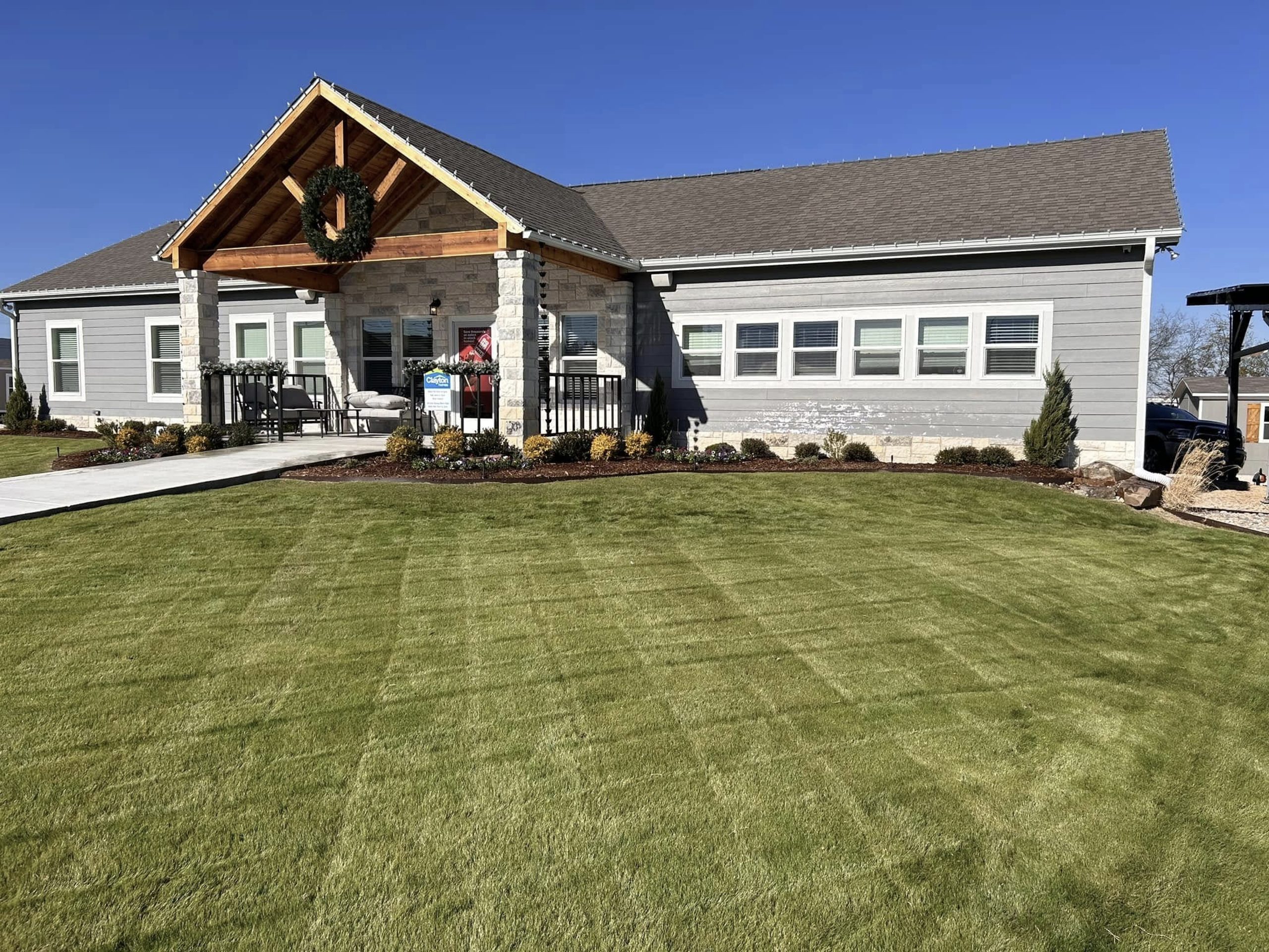 Freshly mowed lawn in front of modern home – professional lawn care services by Hood Lawn Care